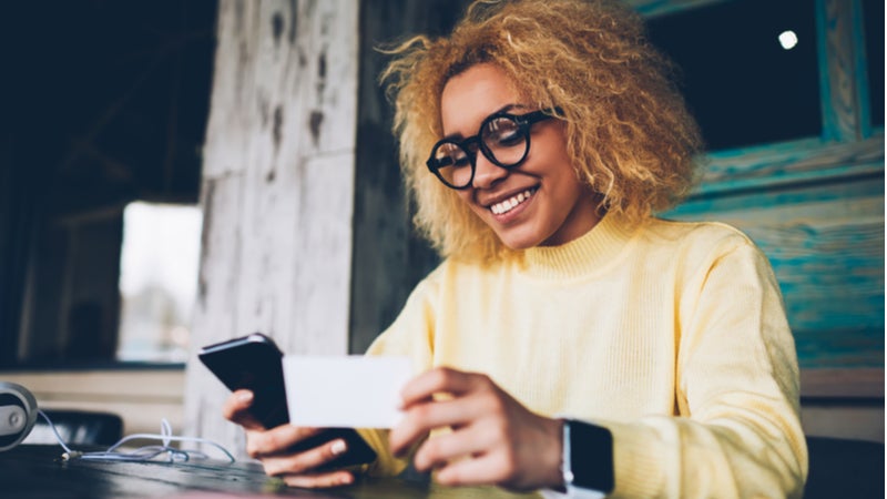 kvinnelig hipster betaler på telefon med kredittkort