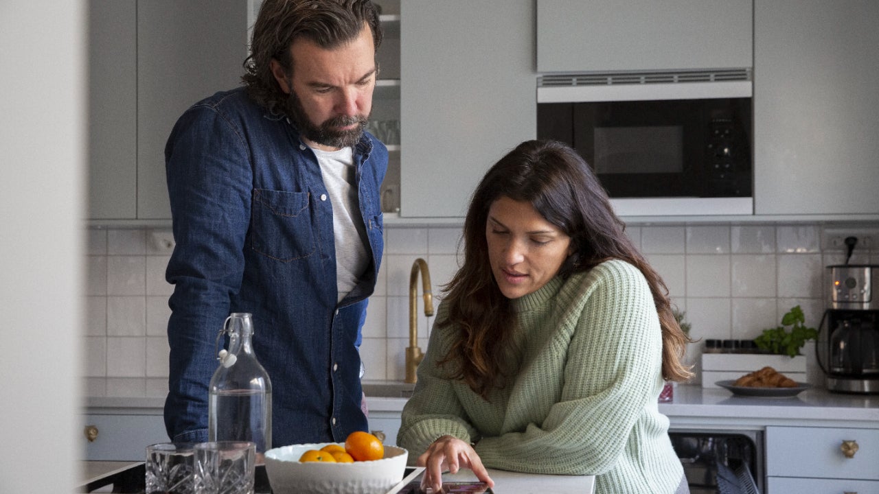 Man and woman at kitchen island looking at mobile phone