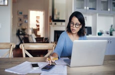 Young woman using a laptop and calculator at home