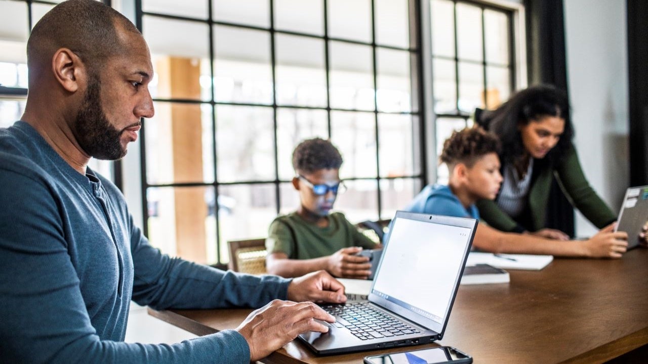 Father working on computer while at home with family