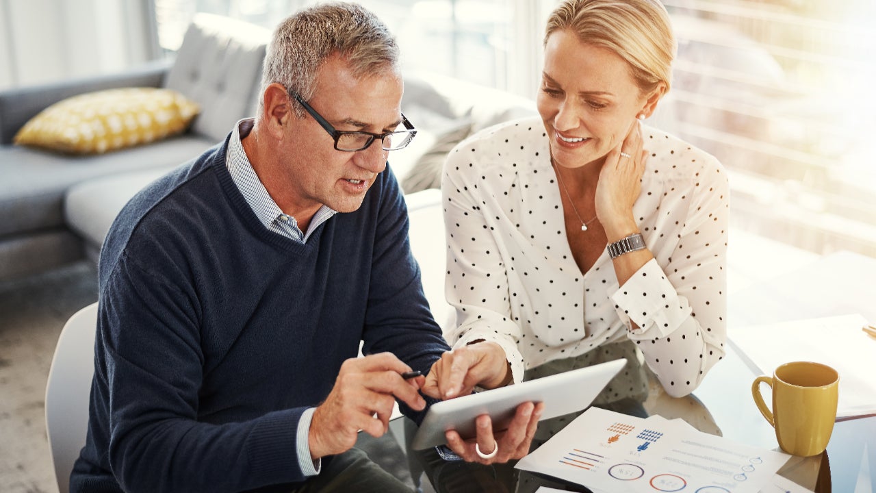 Couple using a digital tablet while going through paperwork at home