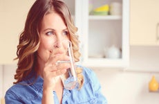 Woman sipping a glass of water © iStock.com/elenaleonova