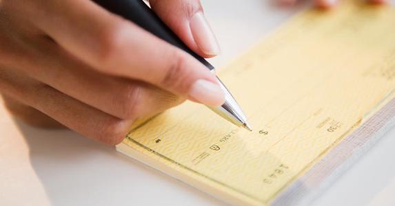 Woman writing amount on check | JGI/Jamie Grill/Blend Images/Getty Images