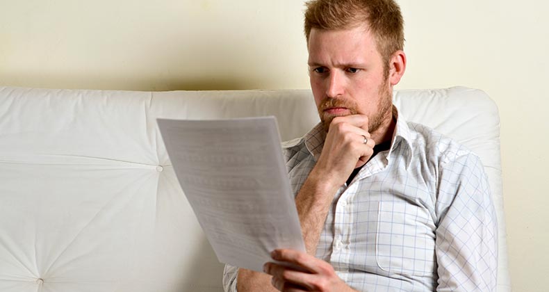 Serious young man reading paperwork © iStock