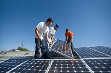 Men installing solar panels | moodboard/Getty Images