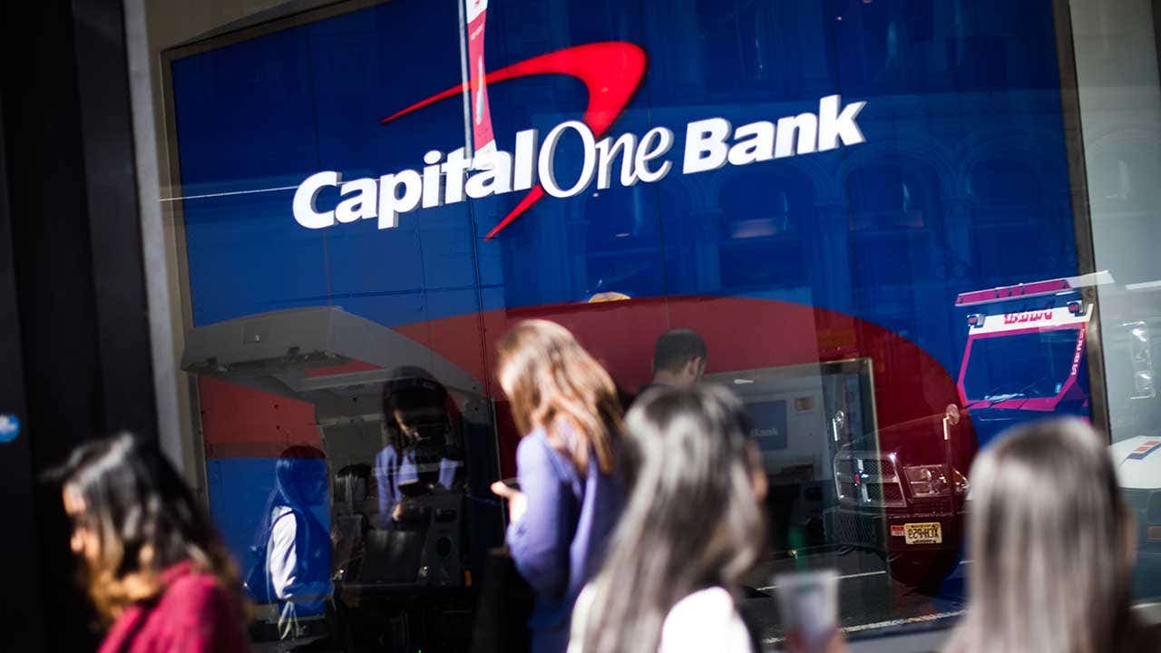 People walking back and forth in front of Capital One Bank entrance.