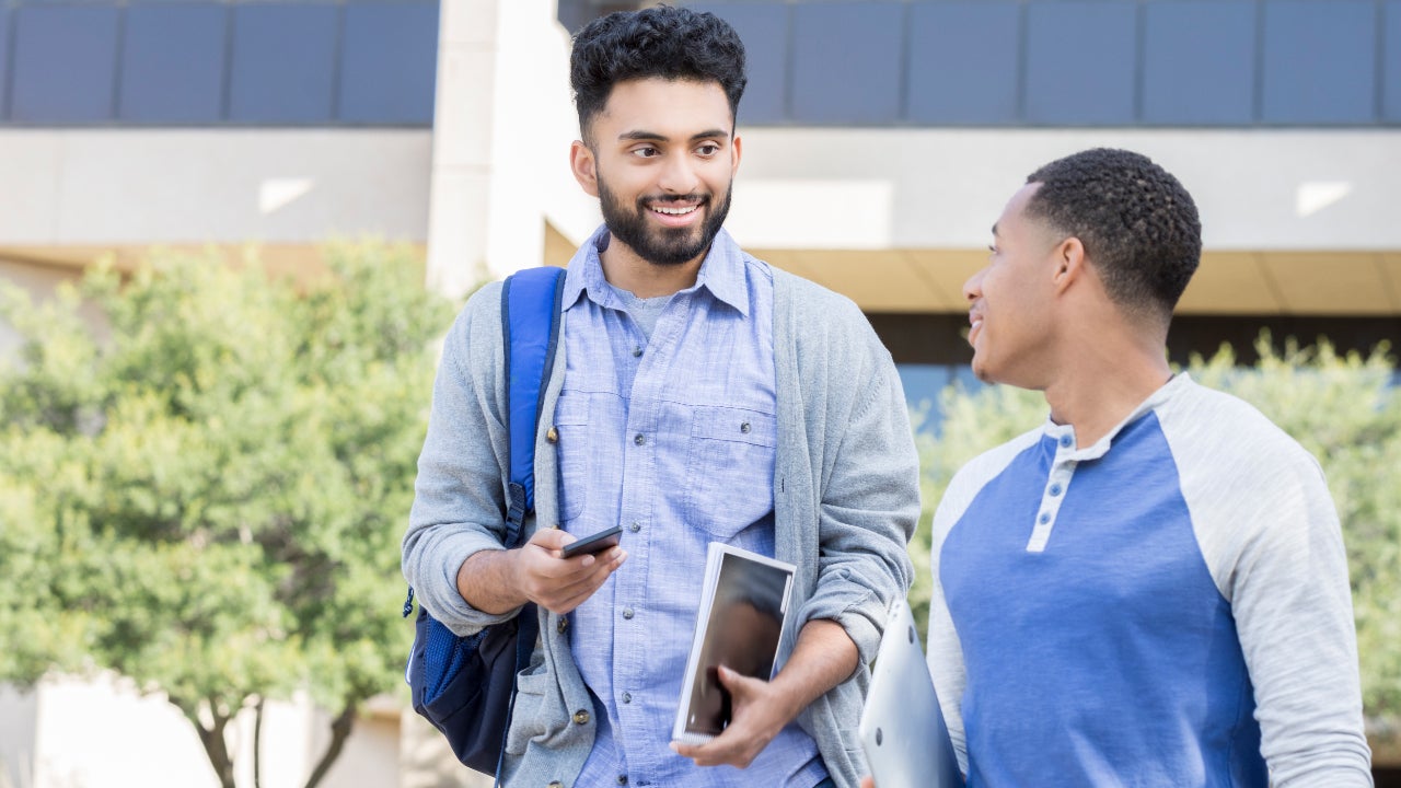 Male friends walk on a college campus.