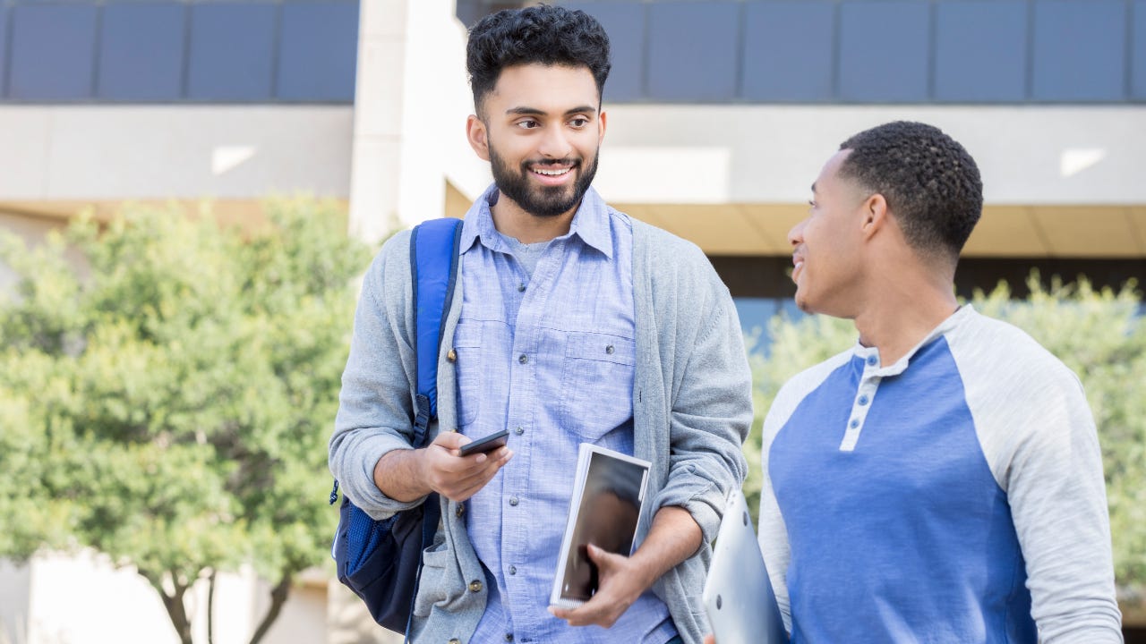 Male friends walk on a college campus.