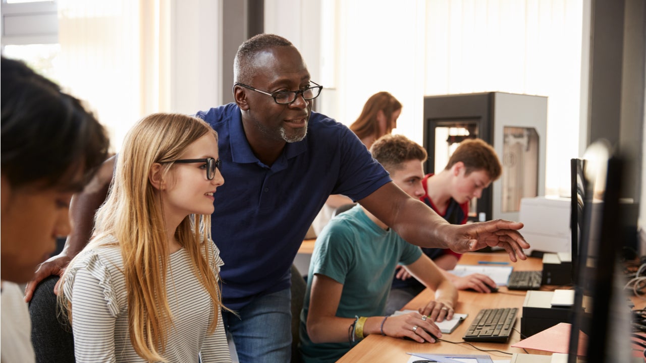 Teacher helps student on computer.