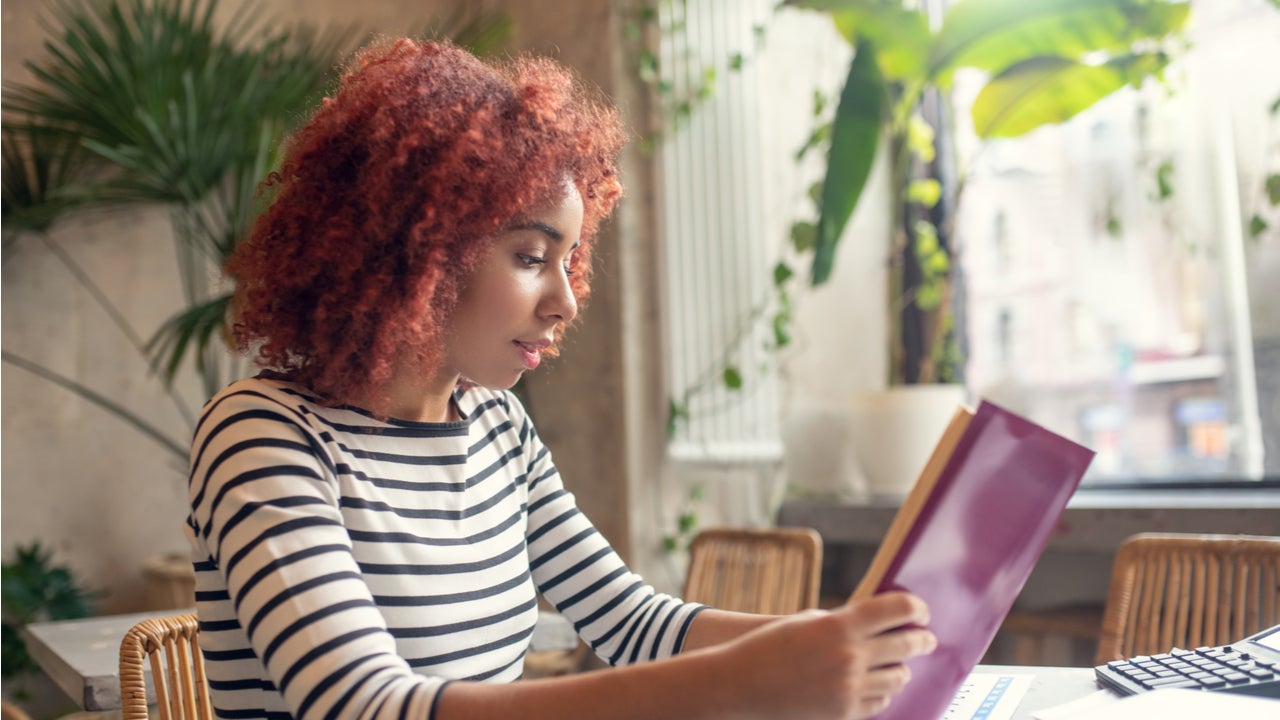 Young woman reads a book at her desk.