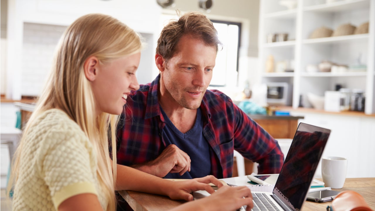 Father and daughter work on a computer together.