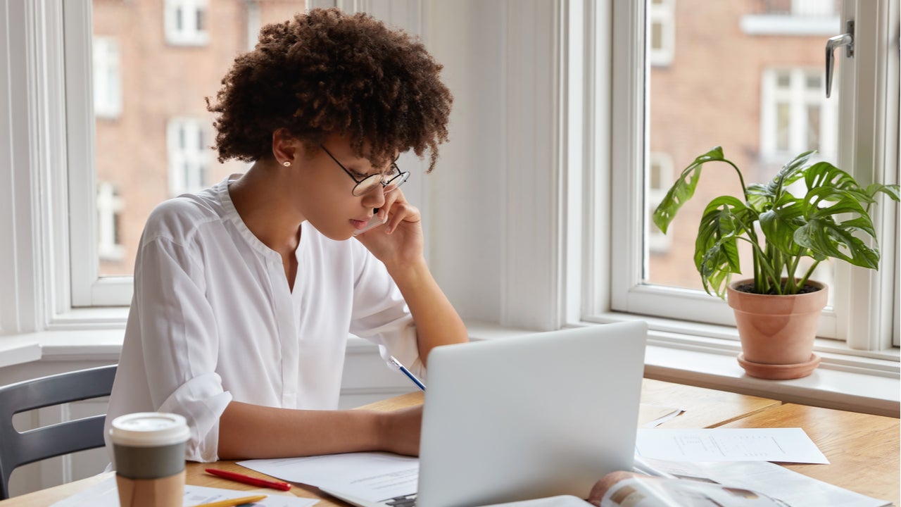 Woman wearing a white shirt and glasses working on laptop