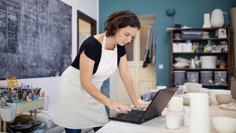 Pottery artist working on laptop at her workshop