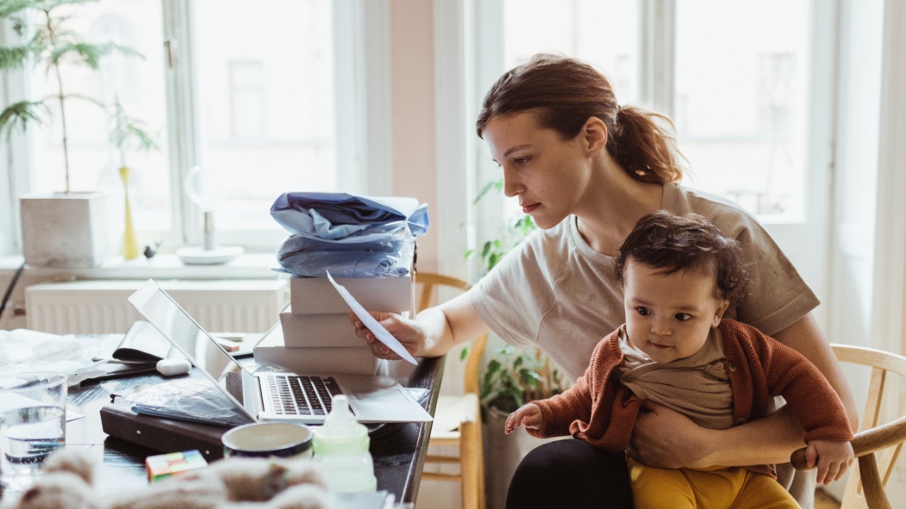 Businesswoman reading document while sitting with baby boy in living room