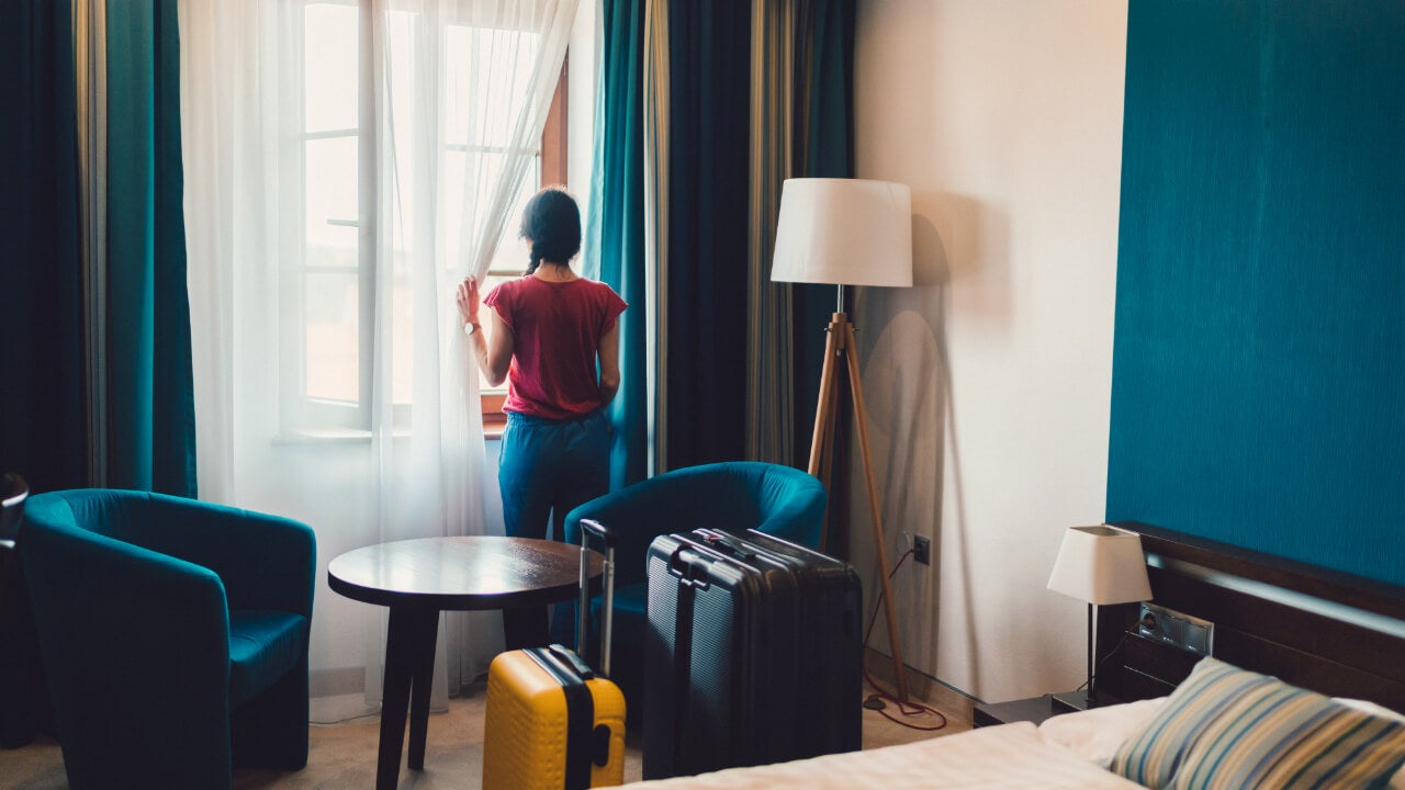 Woman looking out hotel room window