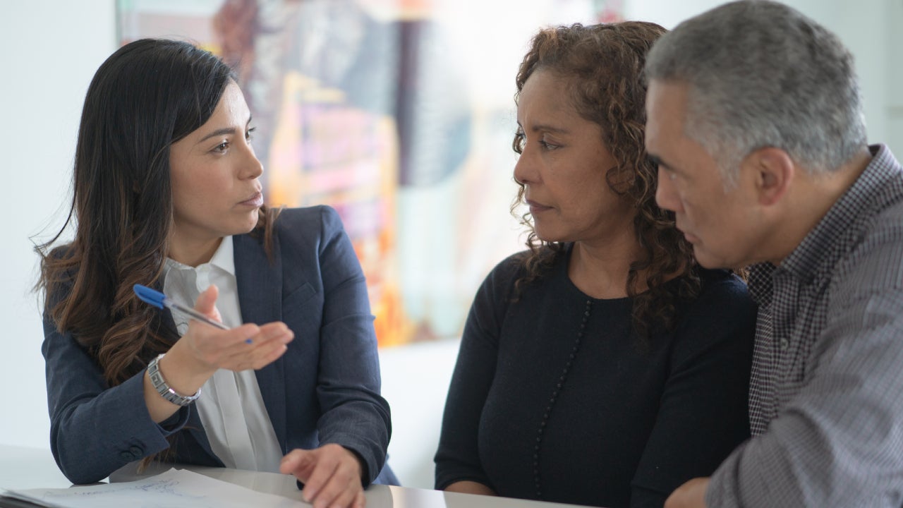 A financial expert is going over the particulars of an insurance policy with a couple who are clients.