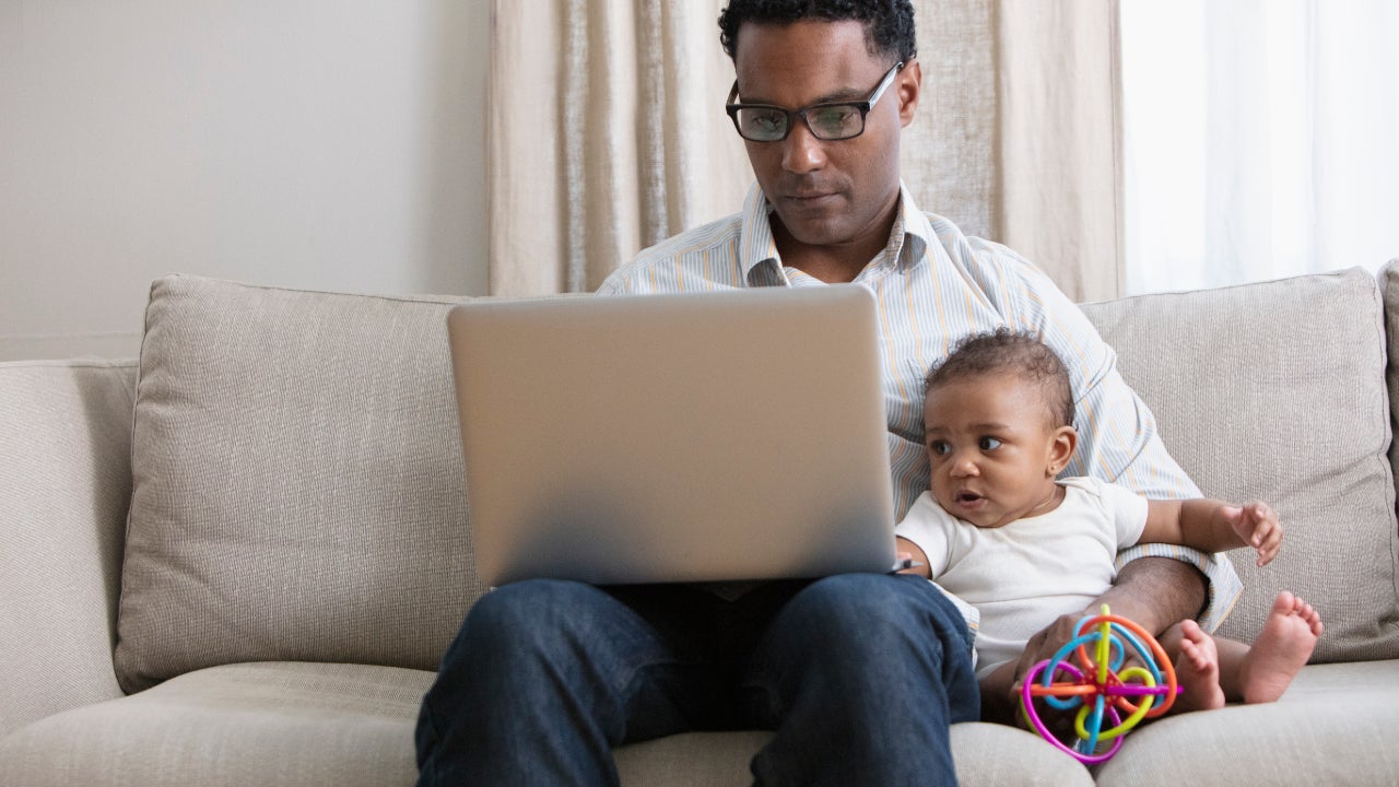 Father working on laptop while taking care of a baby.