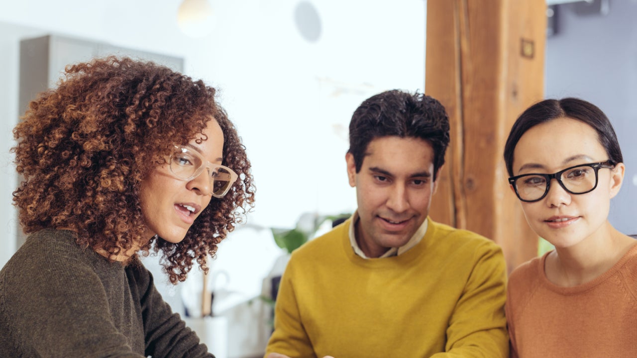 A Hispanic couple is sitting down with a financial expert to discuss a their assets.