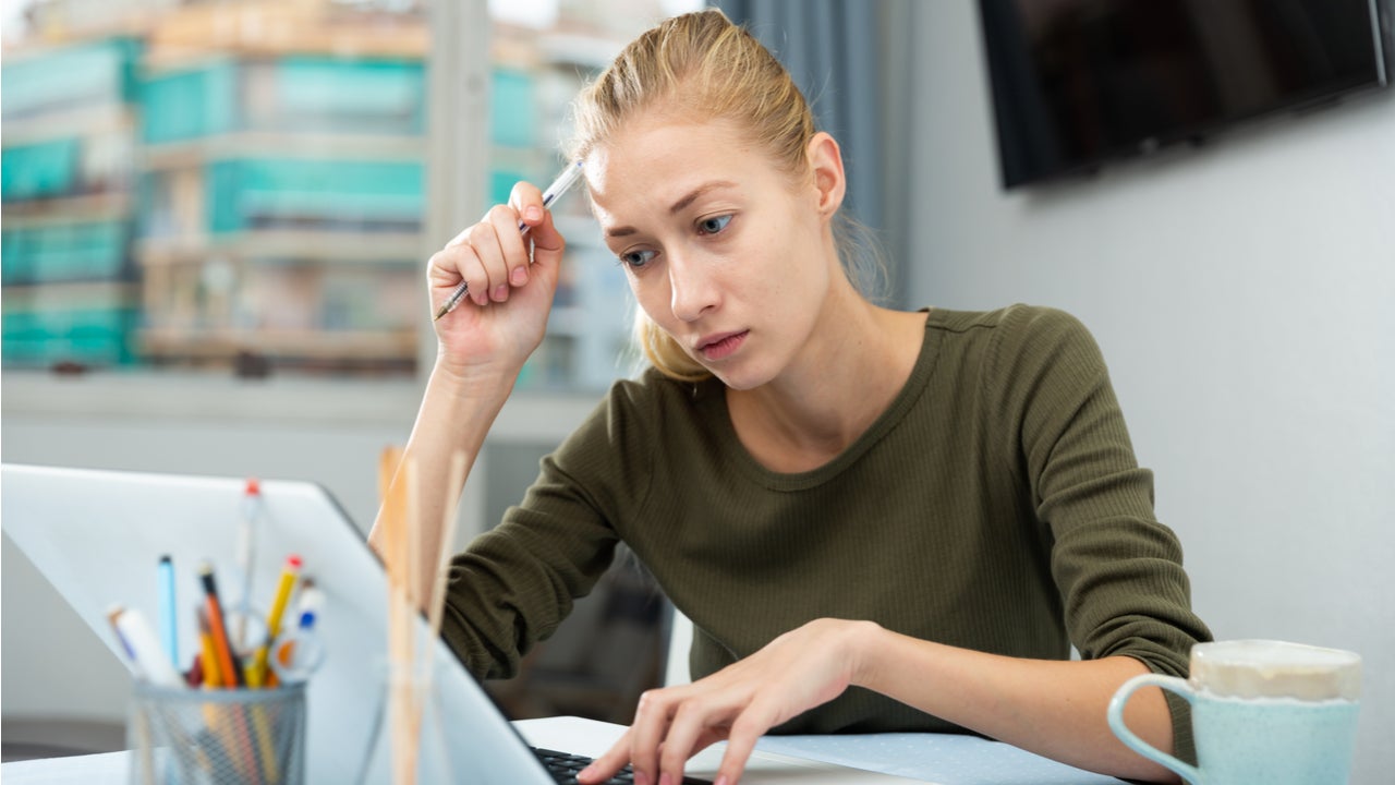 Woman looks concerned while working on laptop