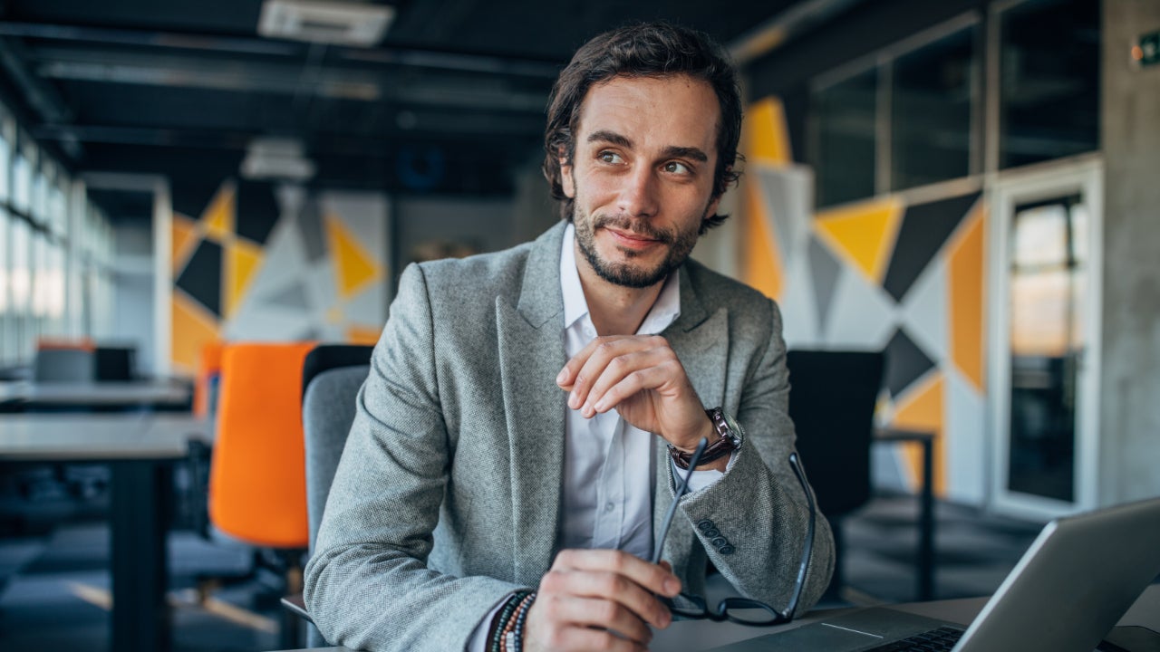 A White man in a business suit sits in an empty office