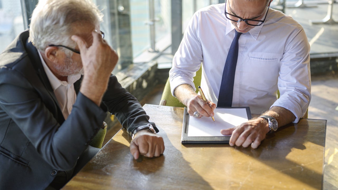 A man sits with his financial advisor looking over some documents.