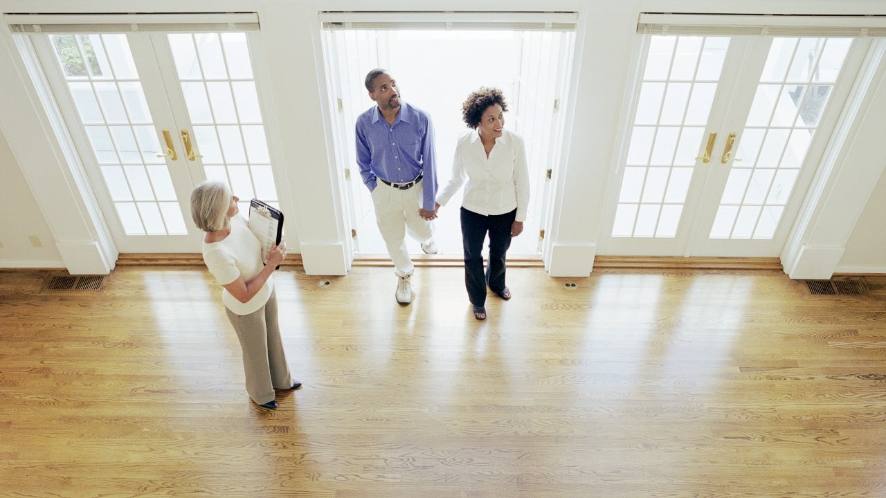 A real estate agent shows buyers a vacant home.