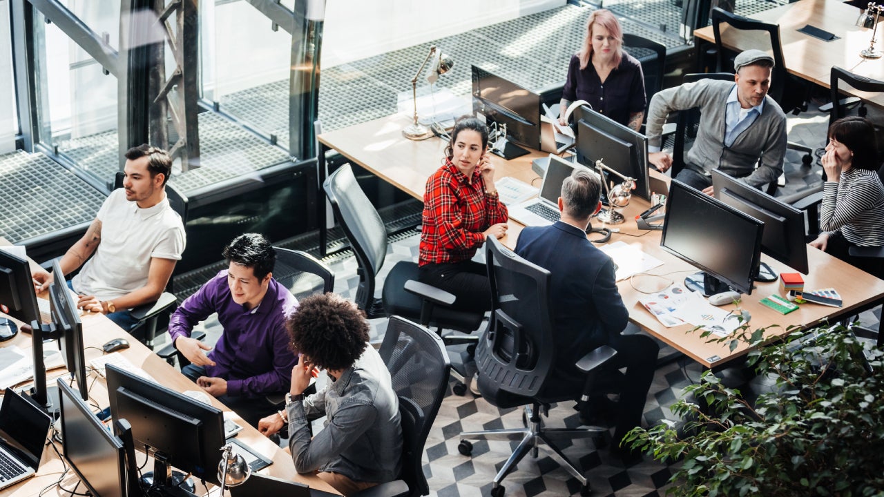 An office area full of people sitting back to back at their computers.