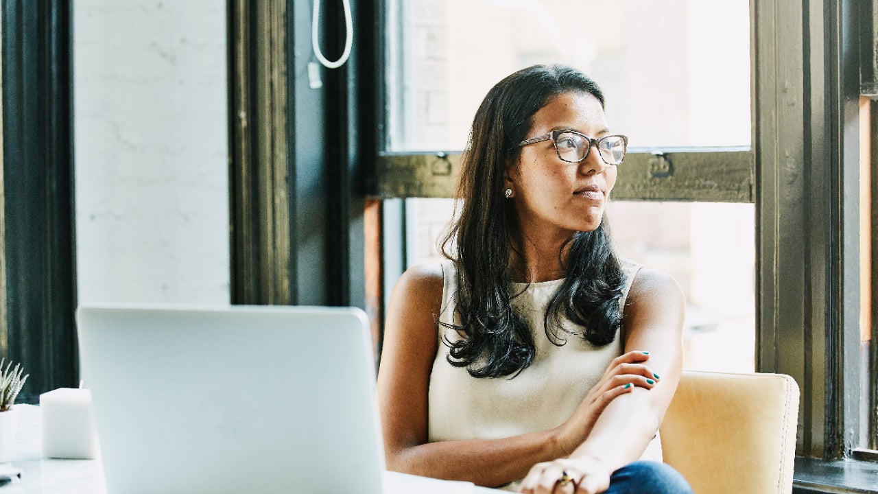 Businesswoman looking out window while seated at desk in office