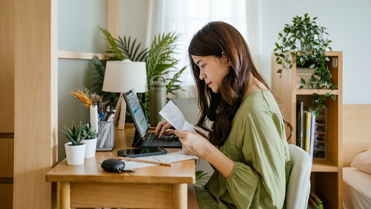 Woman looking at paperwork and working on a laptop