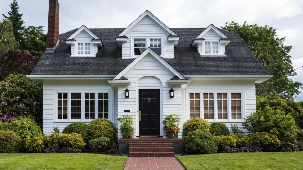 The exterior of a single-family home with dormers and yard