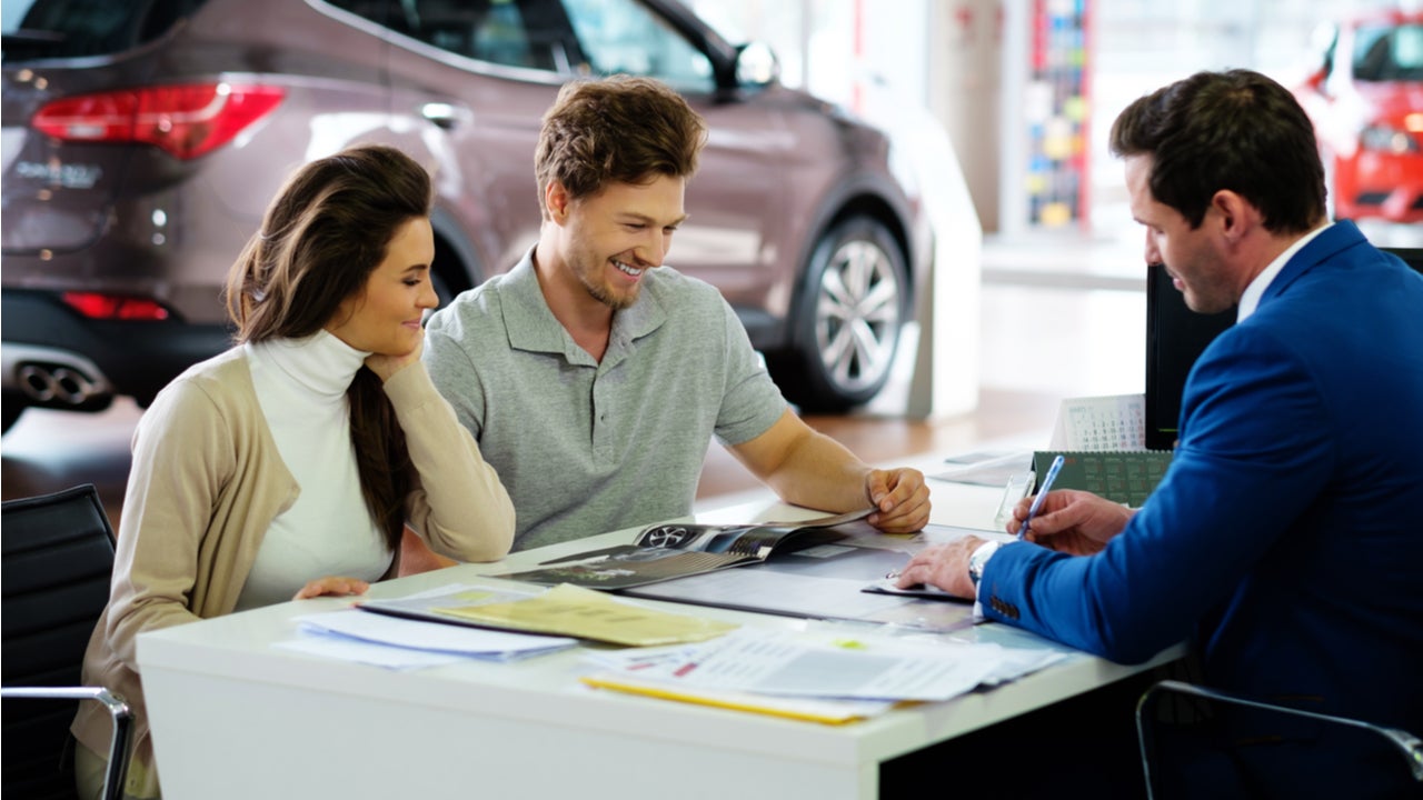 Couple signs paperwork on an auto lease