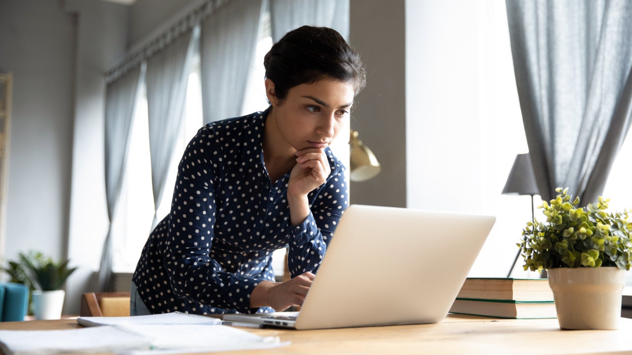 A young Indian woman looks over a laptop