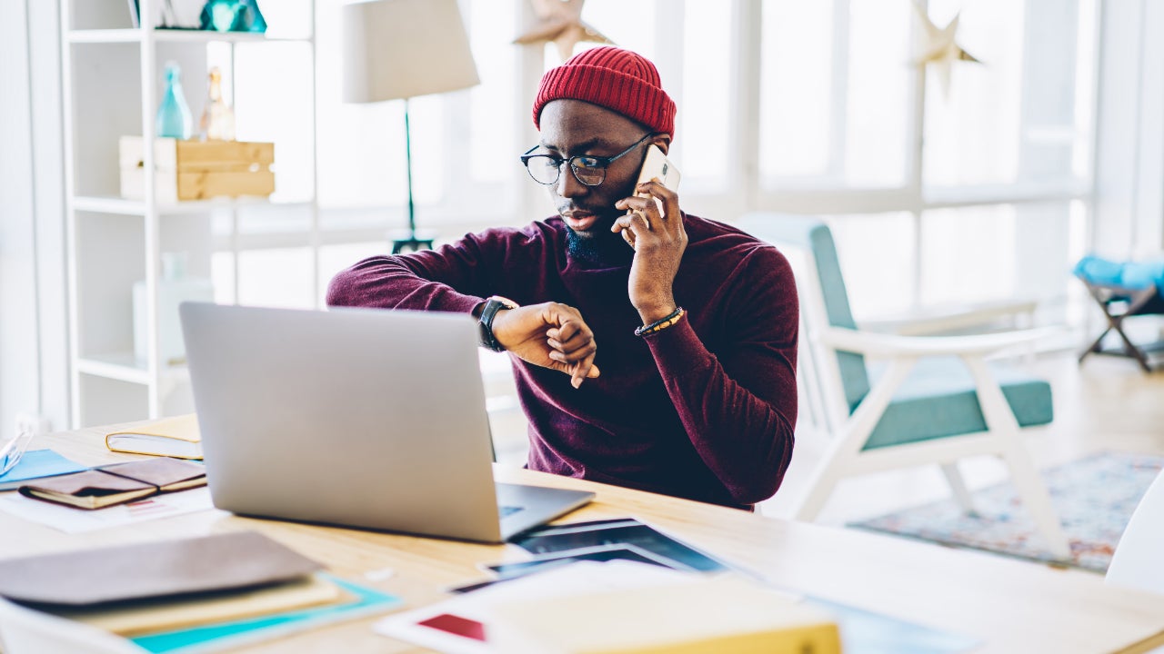 Imprenditore uomo in abbigliamento casual che conversa al cellulare mentre è seduto al tavolo