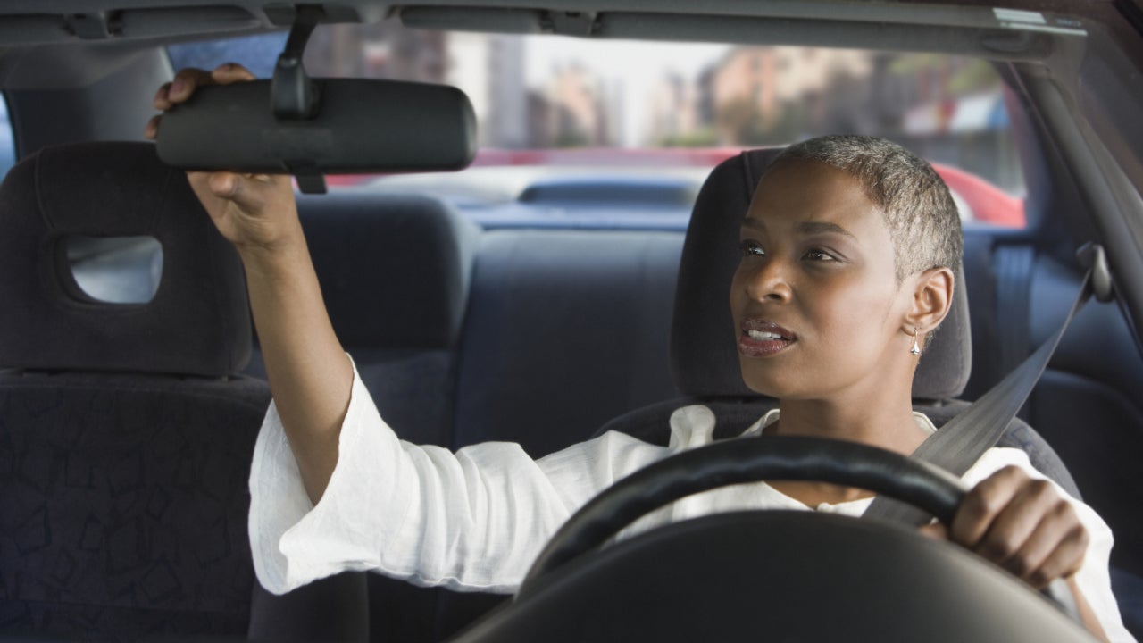 African woman in car adjusting mirror