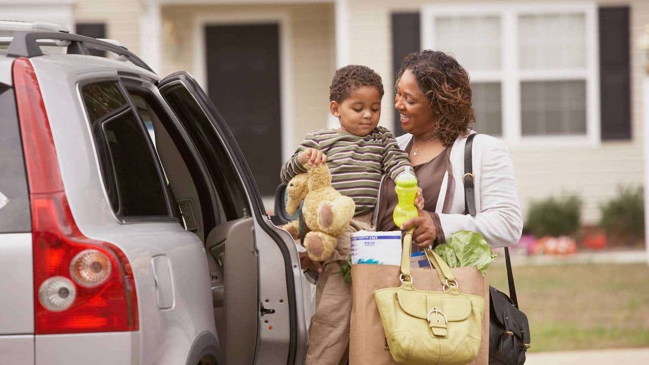 a mom opening the door to sit down her son in his car seat