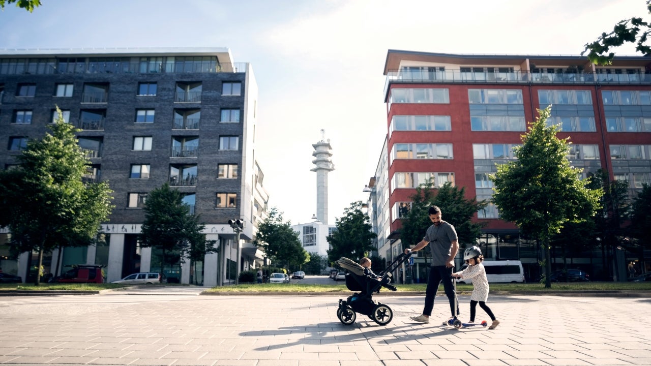 A father with two young children walking in front of condo buildings in the city