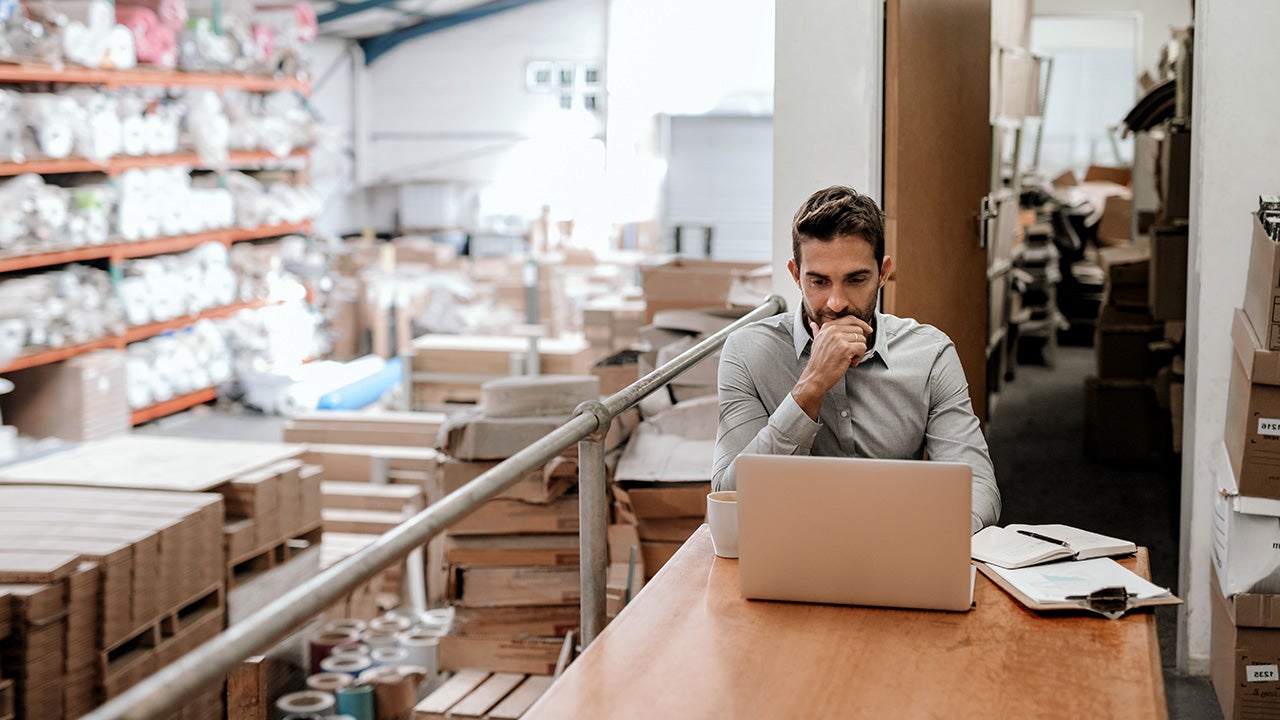 manager working on a laptop in a warehouse