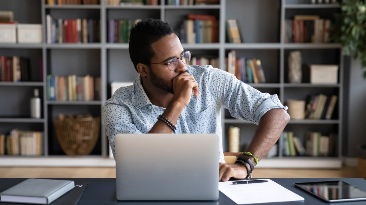 A man at his desk stares out the window thoughtfully