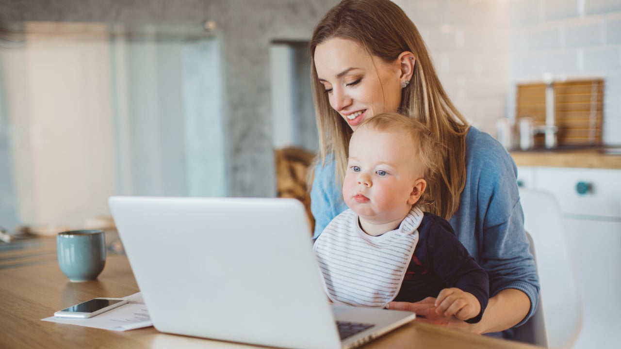 Mother with baby paying bills online.