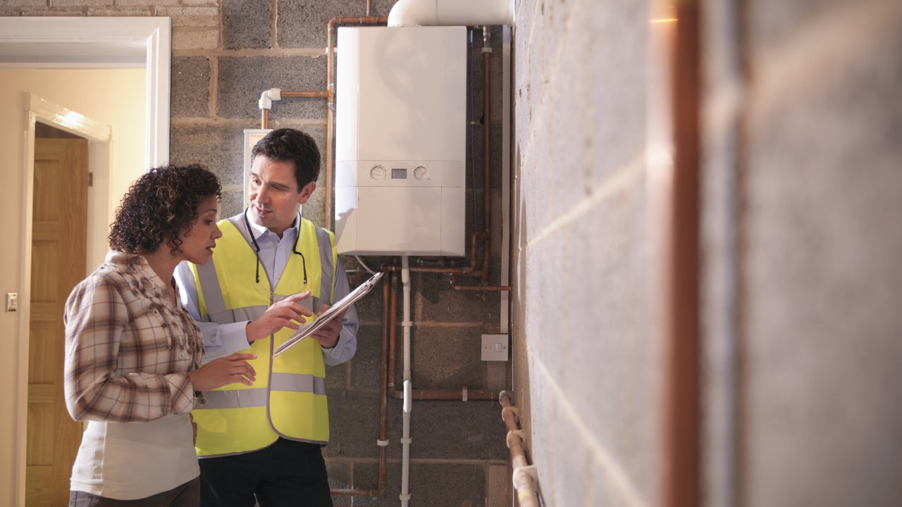 Energy advisor discussing usage of energy efficient boiler with woman in home