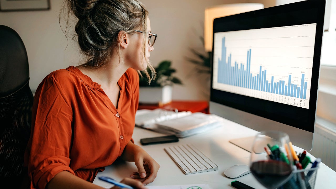 A young woman studies a bar chart on her computer