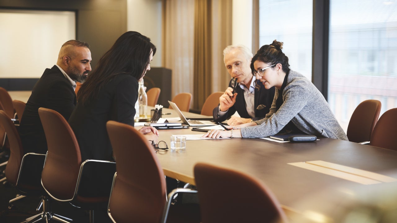 Male and female lawyers discussing over document at conference table in meeting