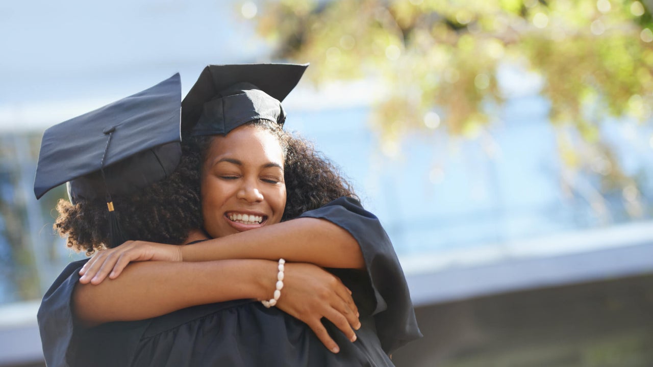 Two college graduates happily embrace