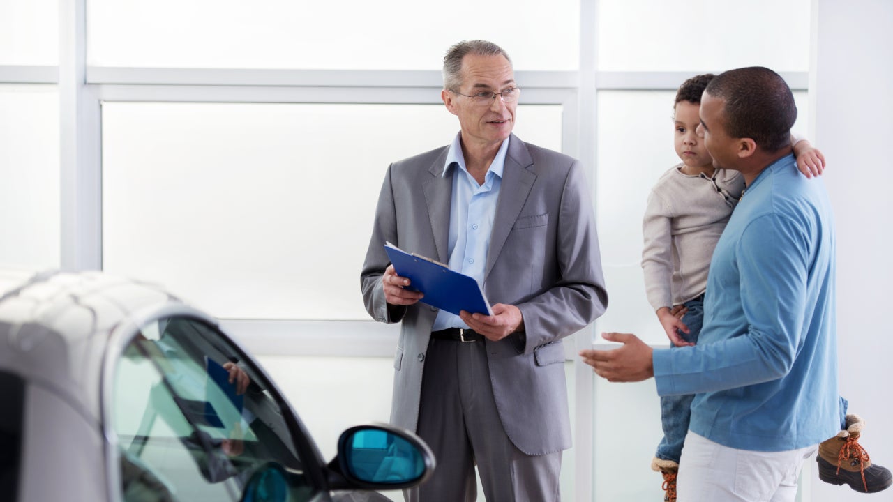 African American father and son discussing with a car salesperson.