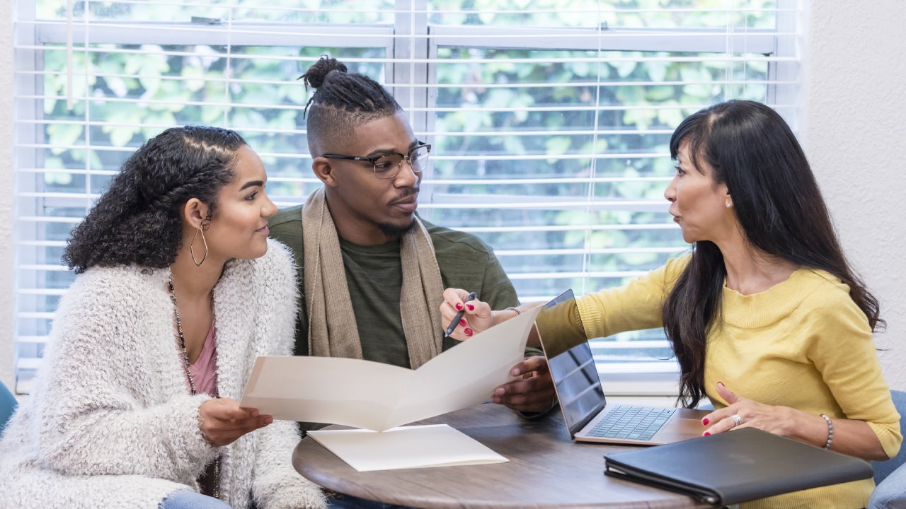 Young couple with advisor, signing paperwork