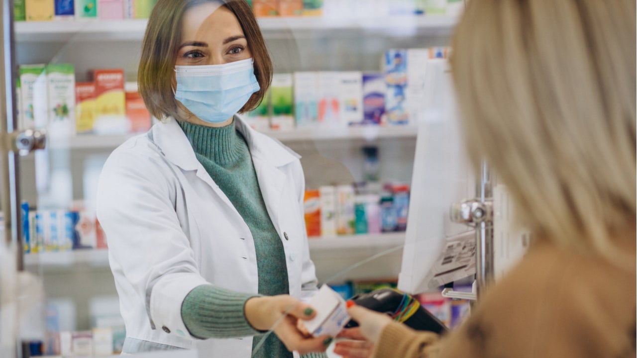 Pharmacist hands medication to customer