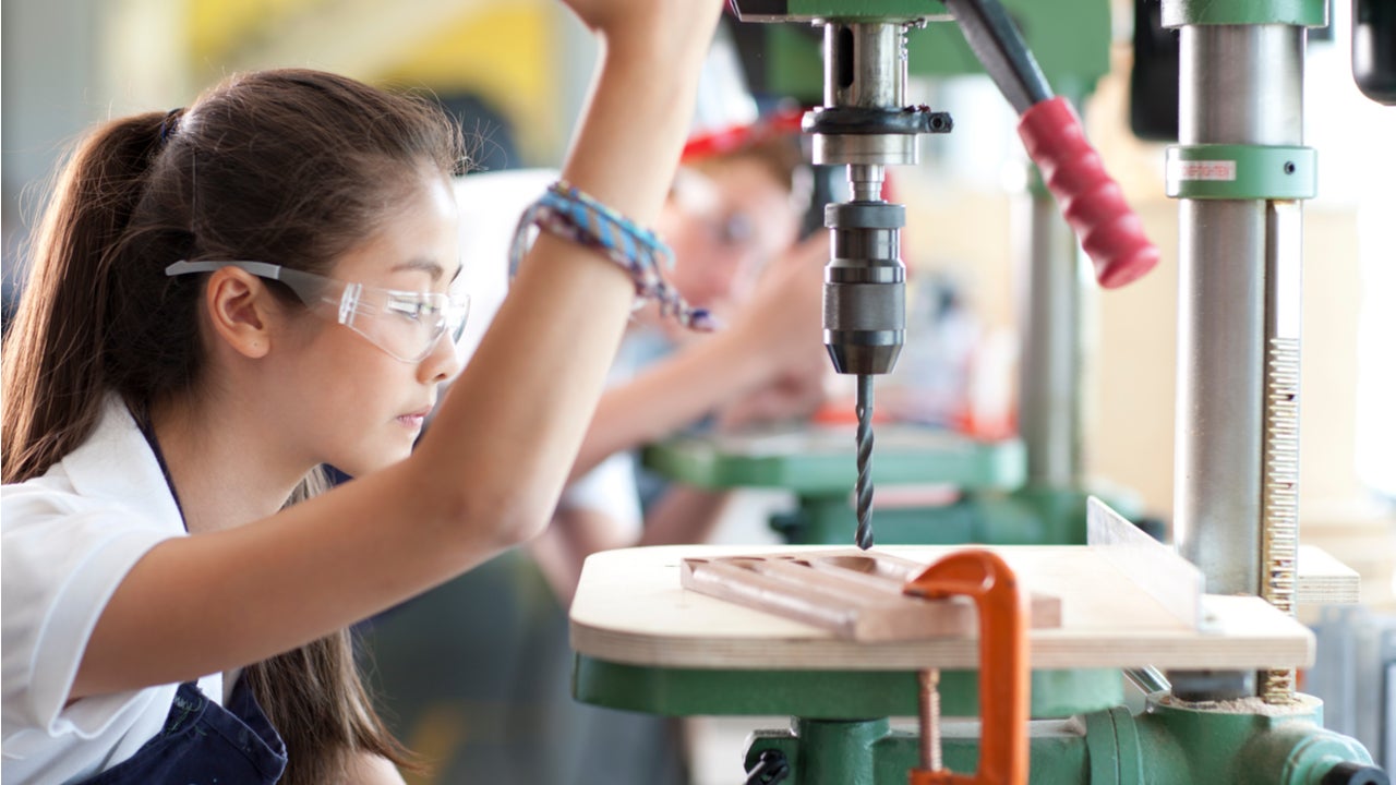 A woman using a drill press.