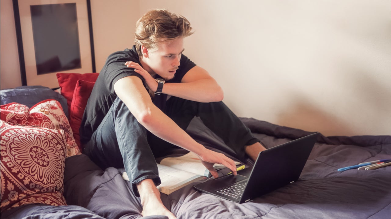 College student studies on a bed