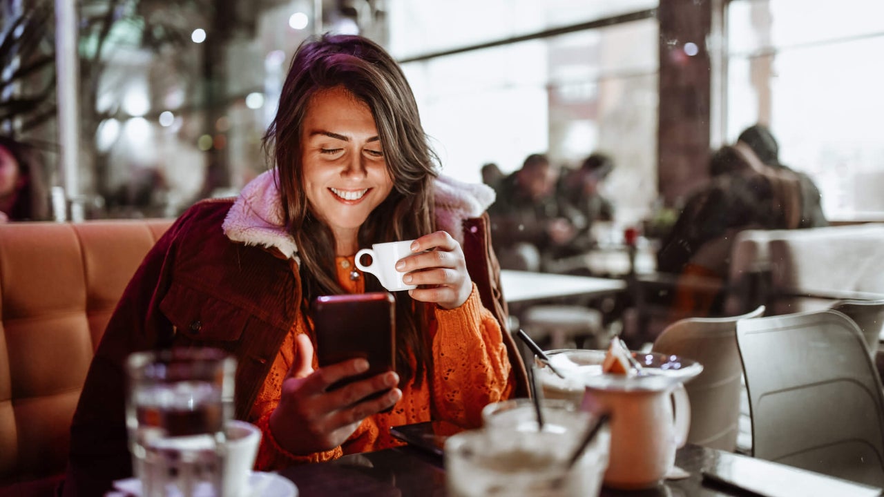 Young woman Enjoying coffee time and using smartphone In restaurant