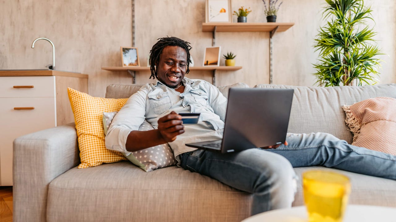 Man shopping from couch with credit card and laptop